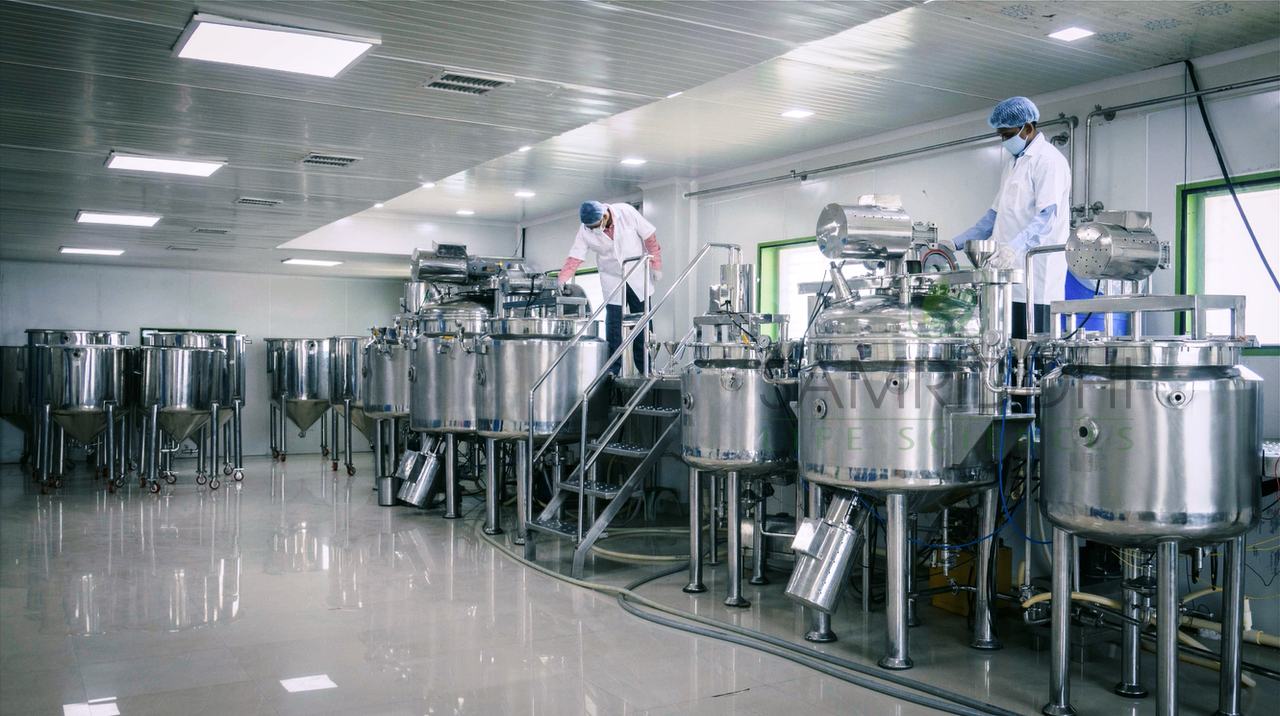 Production floor with stainless steel mixing vessels and technicians at work